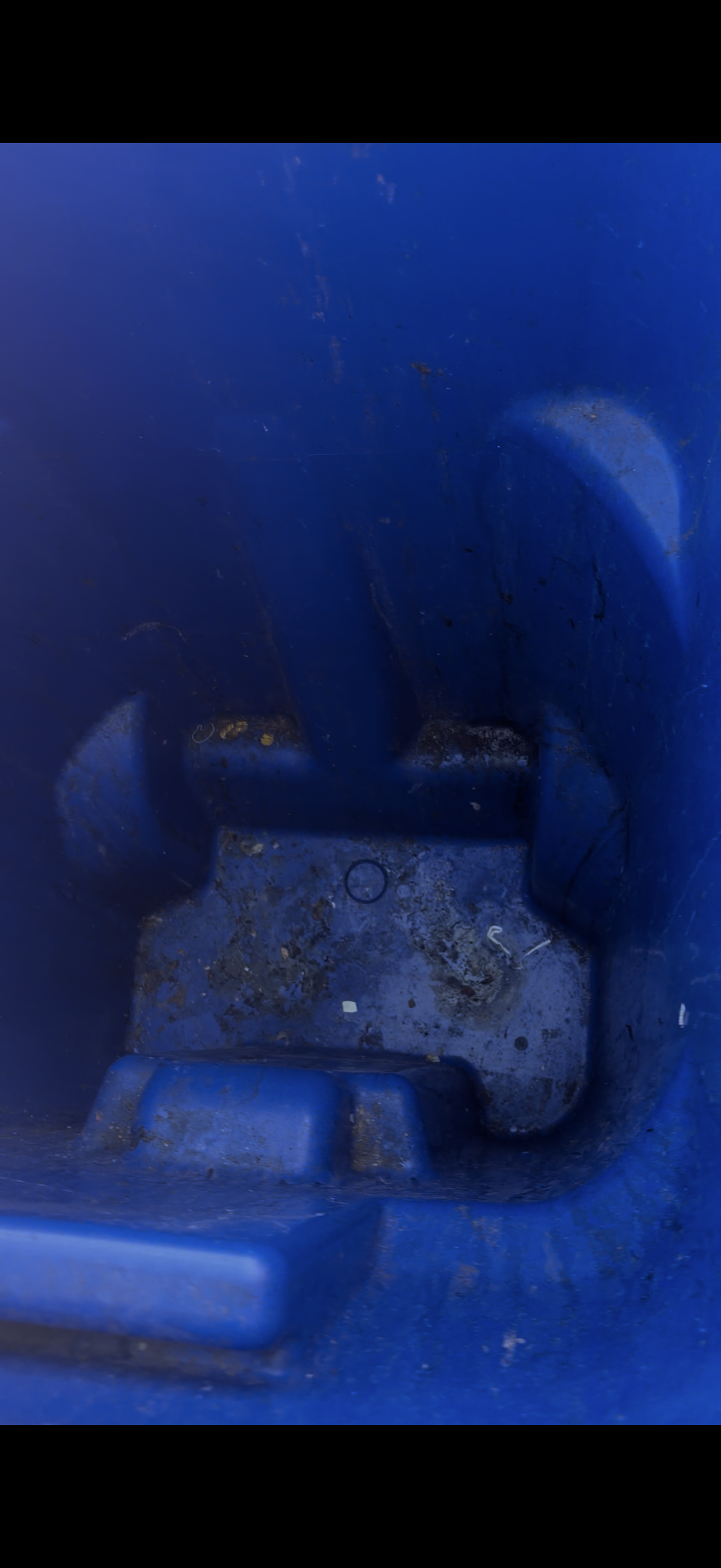 A blue recycling bin with sticky residue and stains on the interior before cleaning.